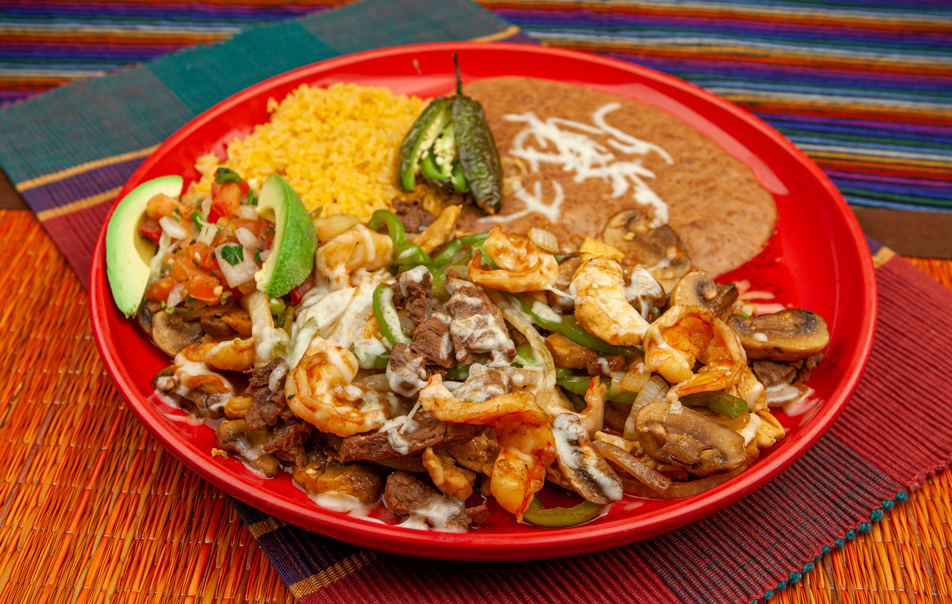 A generous plate of grilled meat, shrimp, vegetables, rice, and beans