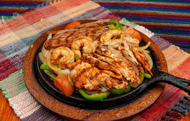 Sizzling fajitas with grilled chicken, shrimp, peppers, and onions